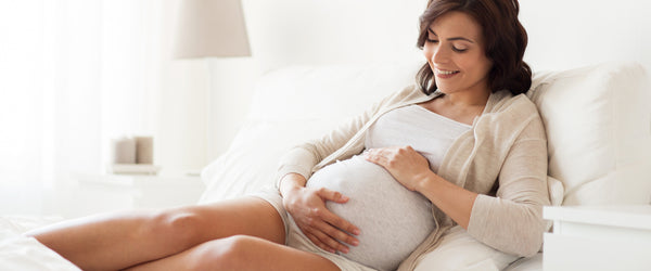 Pregnant woman laying in bed and holding stomach