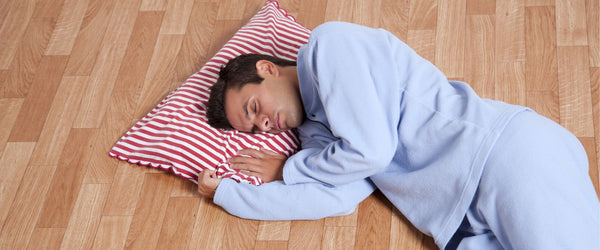 Man sleeping on the floor with just a pillow
