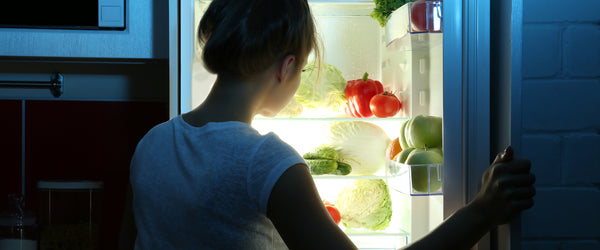Woman opening refrigerator to eat before bed