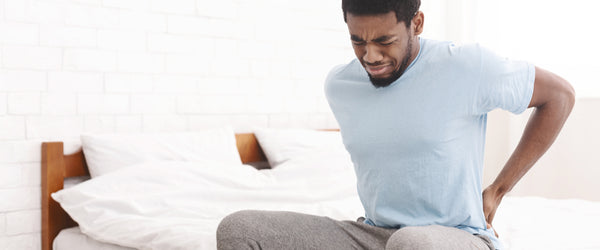 Man with back pain sitting in bed