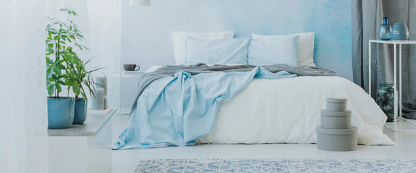 Bed with a white comforter and blue bed sheets