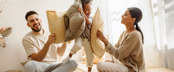 Family sitting on bed having a pillow fight.