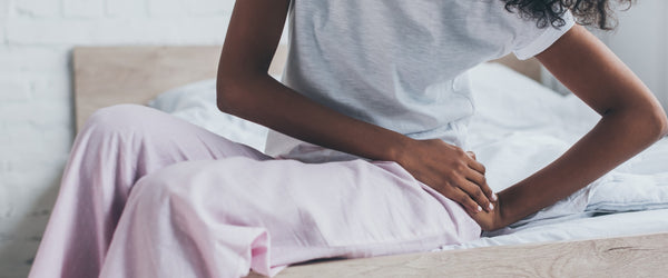 Woman sitting on bed holding her hip because of hip pain from sleeping