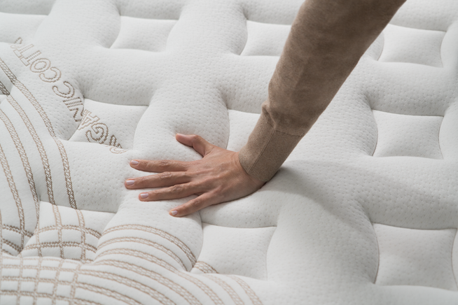 Hand pressing down on cooling mattress with an organic cotton cover.